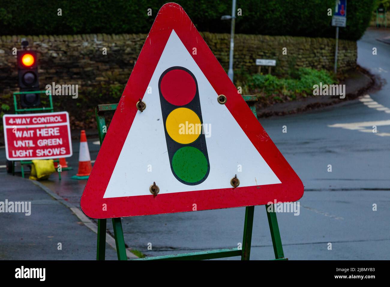 A temporary traffic light sign warning of roadworks ahead. There is 4 way traffic control at a junction of 4 roads in Baildon, Yorkshire. Stock Photo