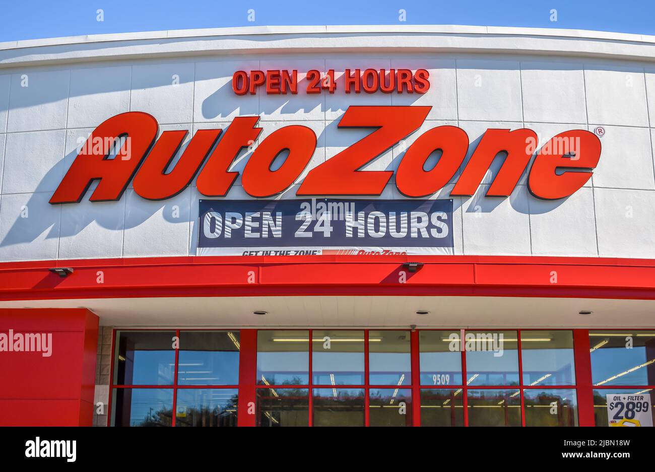 AutoZone auto parts store's exterior facade brand and logo signage in red,  italic letters on a white background on a sunny day with blue sky Stock  Photo - Alamy