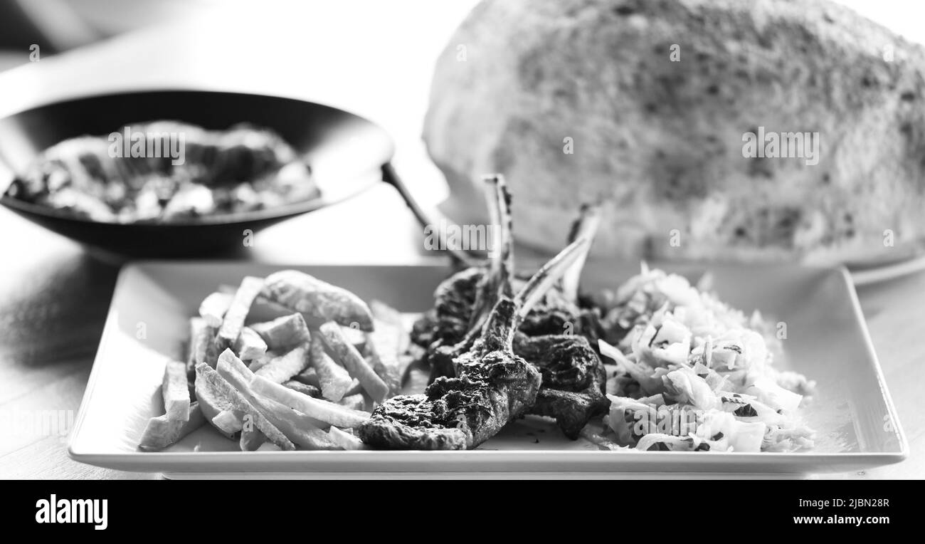 delicious grilled lamb chopsticks with french fries, pesto sauce & mix of lettuces Stock Photo