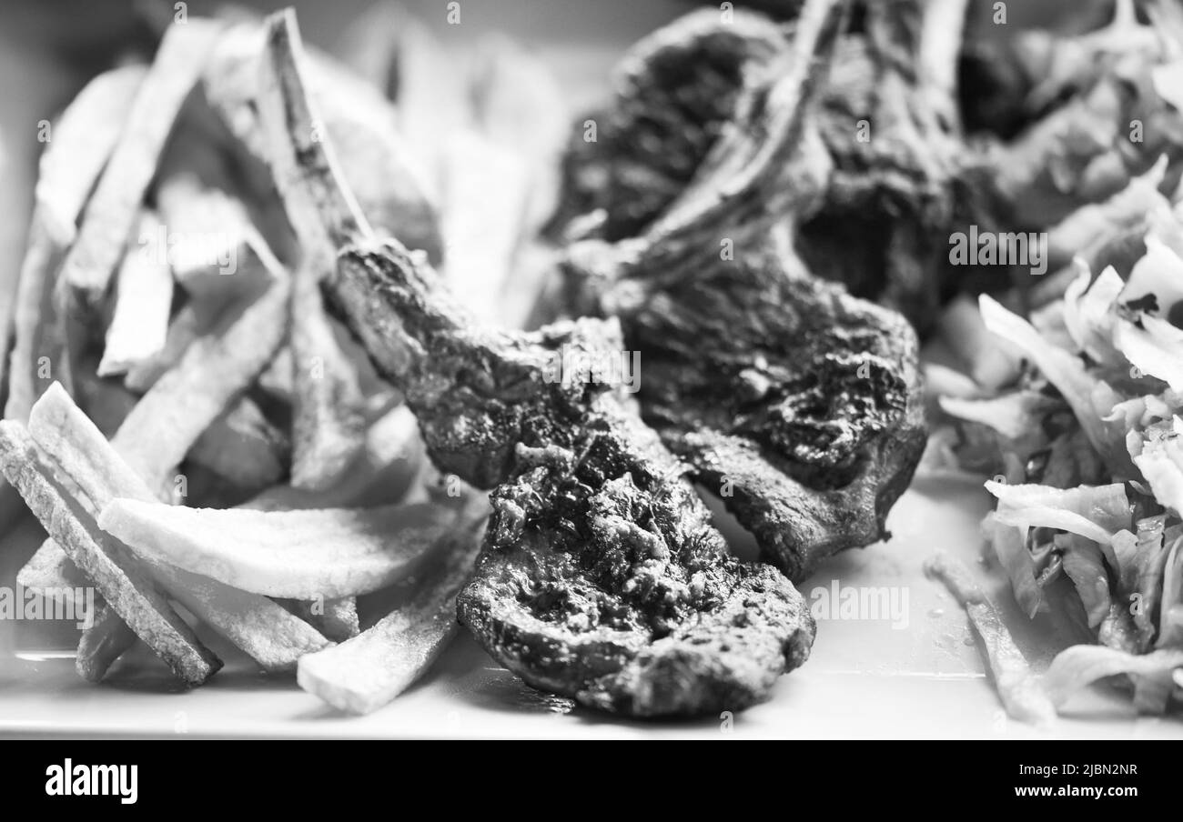 delicious grilled lamb chopsticks with french fries, pesto sauce & mix of lettuces Stock Photo