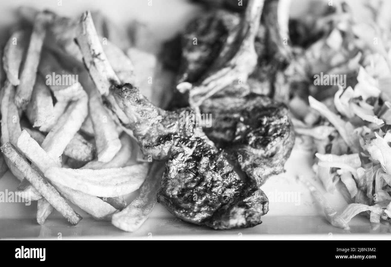 delicious grilled lamb chopsticks with french fries, pesto sauce & mix of lettuces Stock Photo