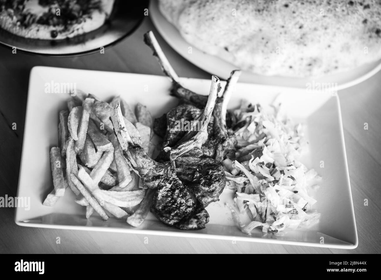 delicious grilled lamb chopsticks with french fries, pesto sauce & mix of lettuces Stock Photo