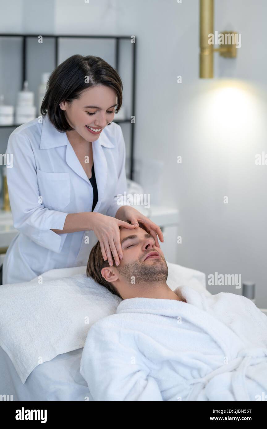 Female Professional In A Mask Doing Face Massage To A Male Client Stock