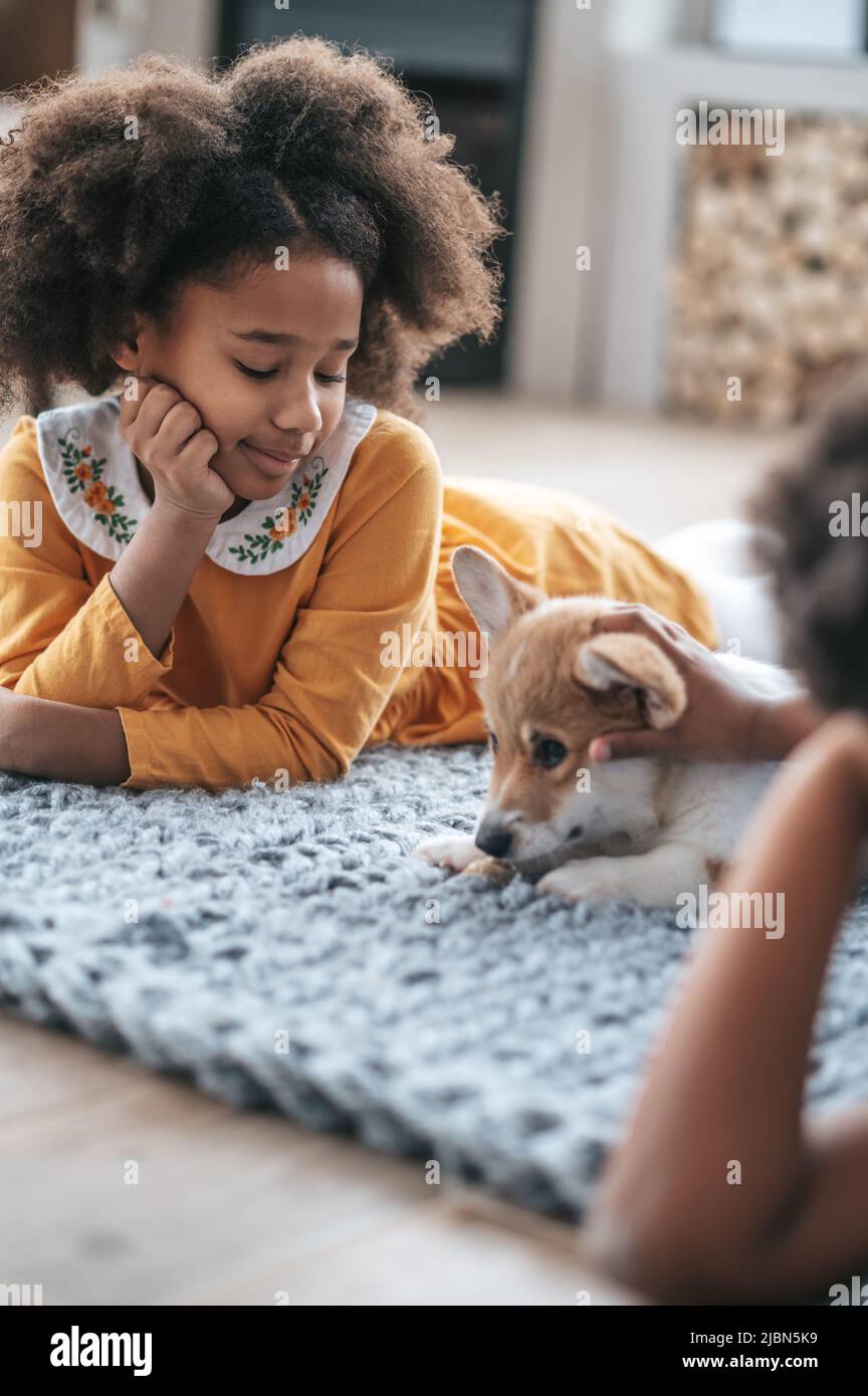 Kids lying on the floor next to their pet and looking happy Stock Photo