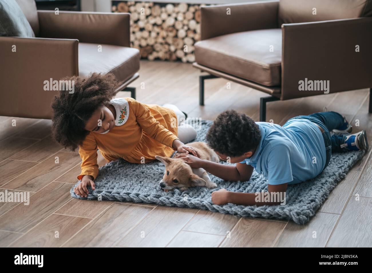 Kids lying on the floor next to their pet and looking happy Stock Photo