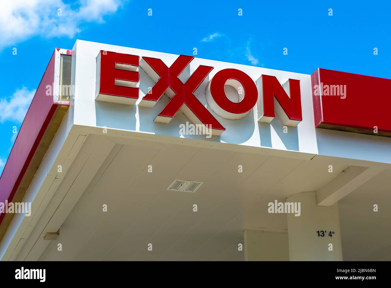 Exxon gas station's outdoor facade brand and logo signage in red letters on white against a blue sky with white clouds in southwest Charlotte, NC. Stock Photo