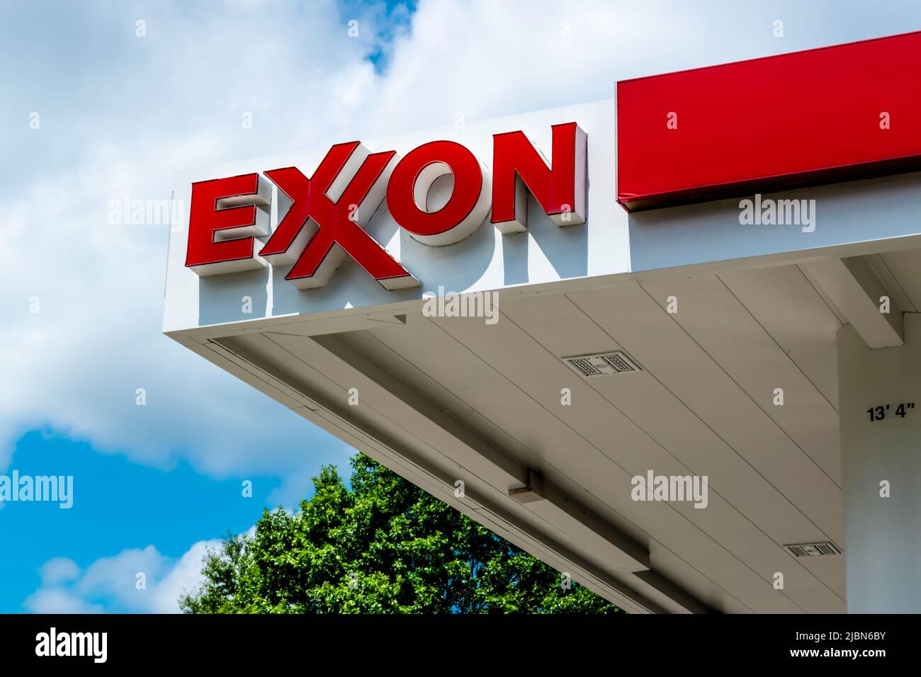 Exxon gas station's outdoor facade brand and logo signage in red letters on white against a blue sky with white clouds in southwest Charlotte, NC. Stock Photo