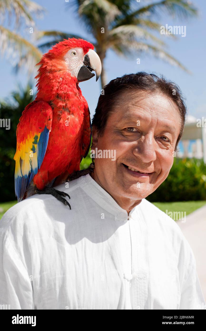 Victor, a tai chi instructor, calls on Billy the parrot, as part of the Macaw Ritual—one of several daily rituals that take place at Live Aqua Resort Stock Photo