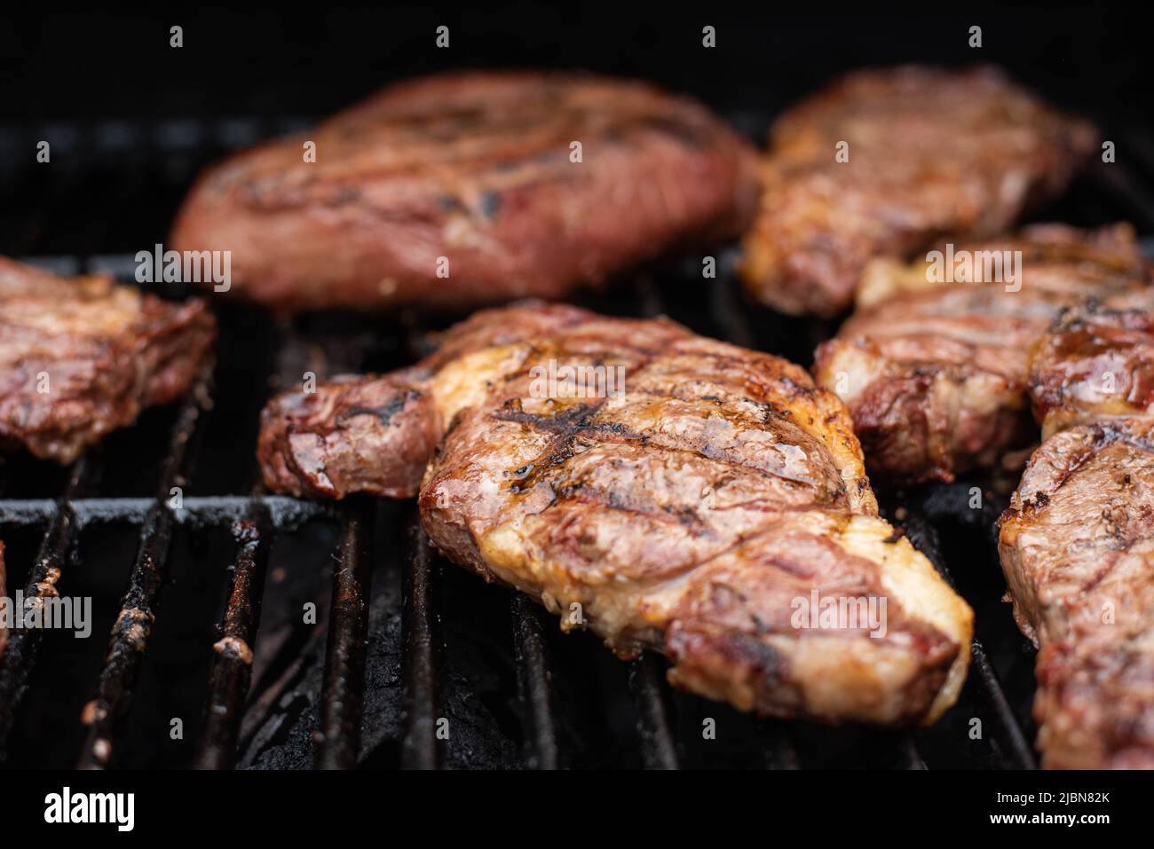 Steaks cooking on a grill. - Stock Image