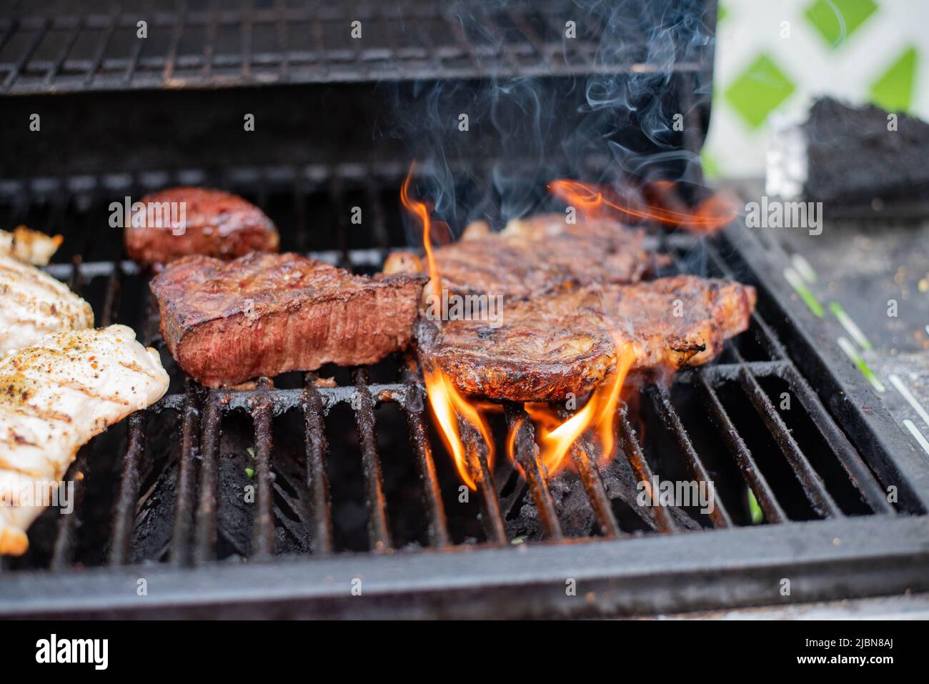 Steaks cooking on a grill. - Stock Image
