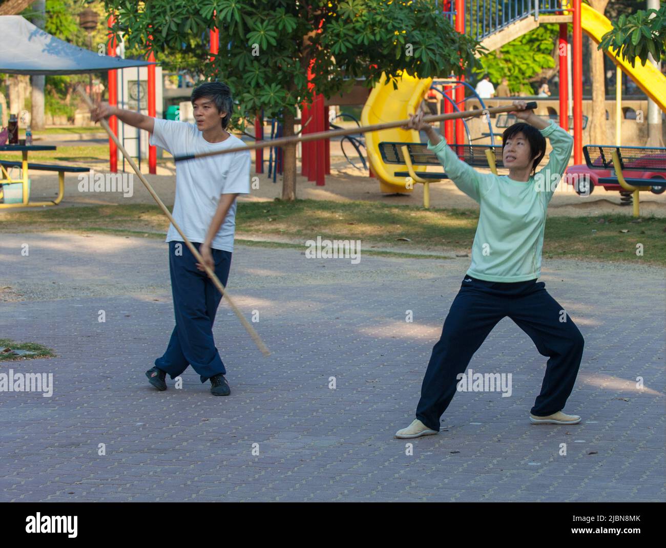 Morning Tai Chi exercise with a wooden stick in Lumpini Park Bangkok Thailand Stock Photo