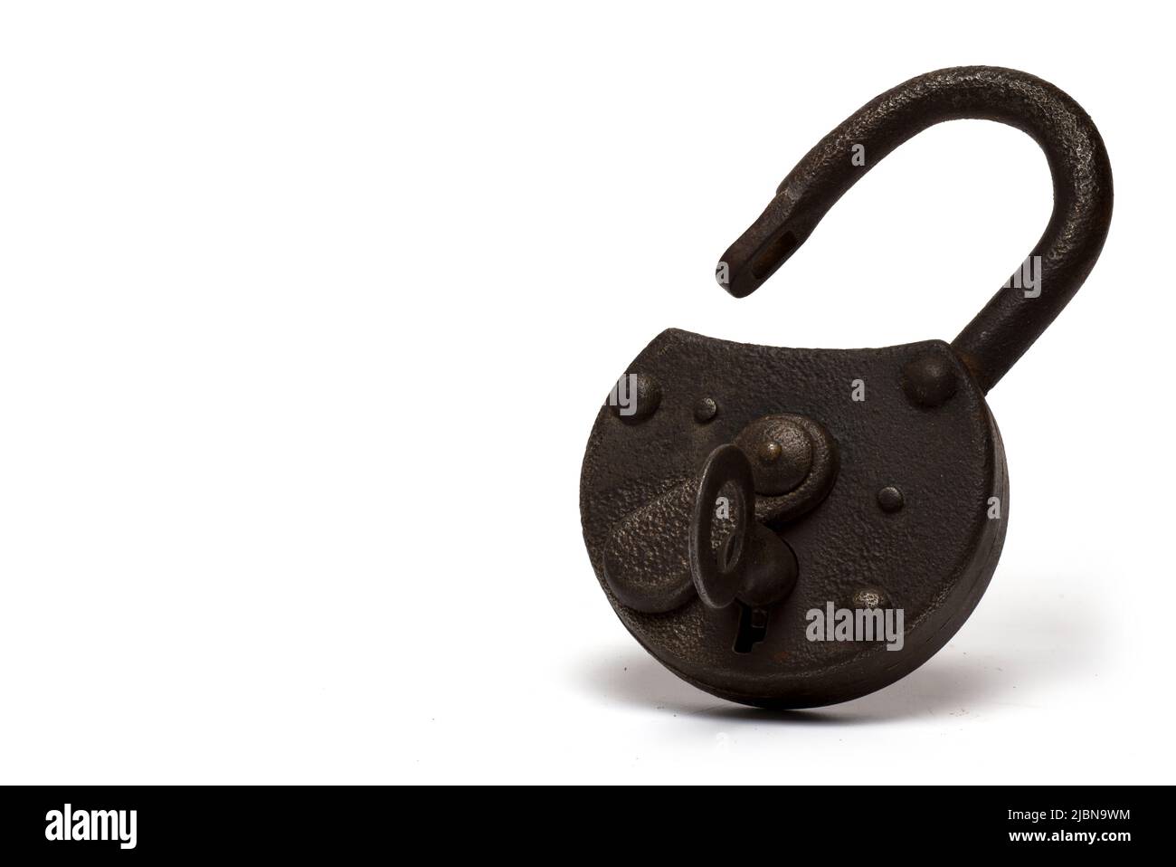 Close up of old rusty open shackle lock with open lock guard and pinned key on white background Stock Photo