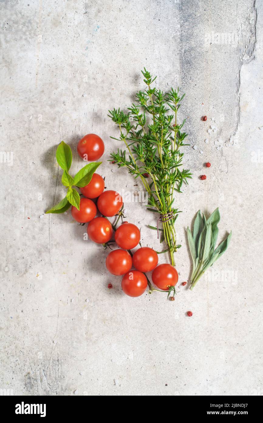 Summer savory with cherry tomatoes and sage on concrete background Stock Photo