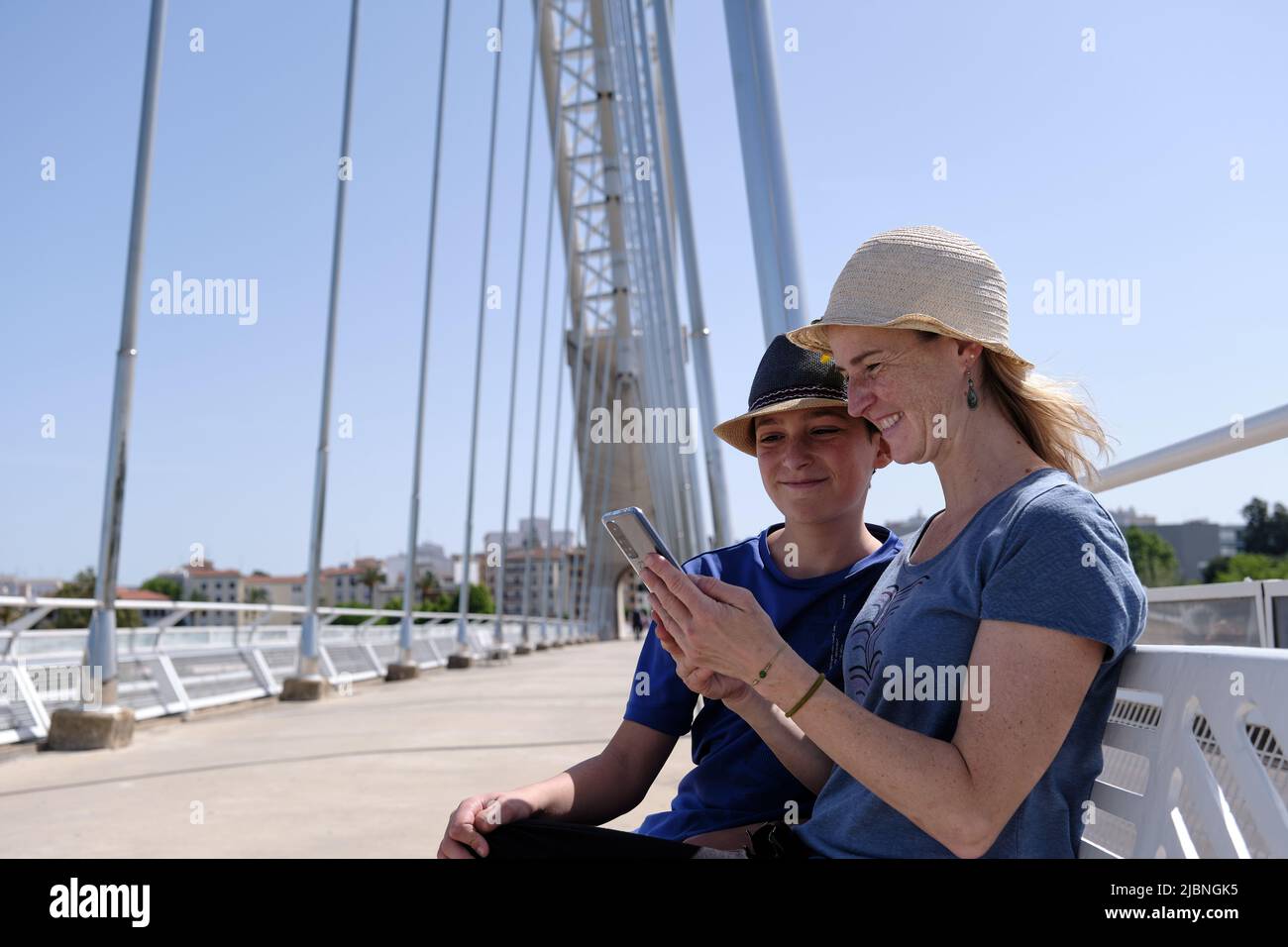 Cheerful mother and son using smartphone on bridge Stock Photo