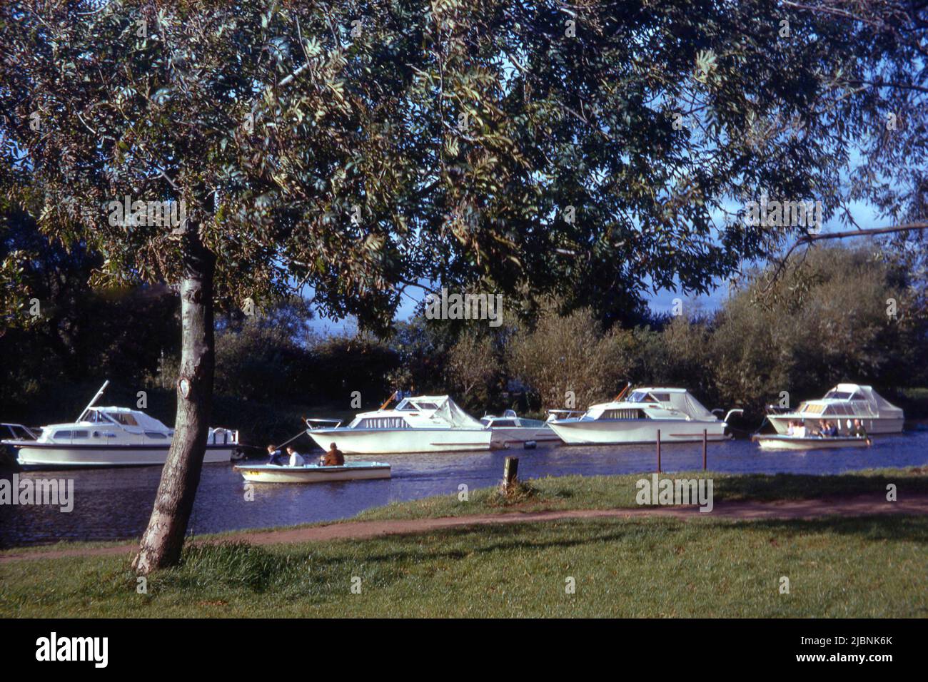 Attractive riverside scene with boats moored and craft passing on the river (1969) Stock Photo