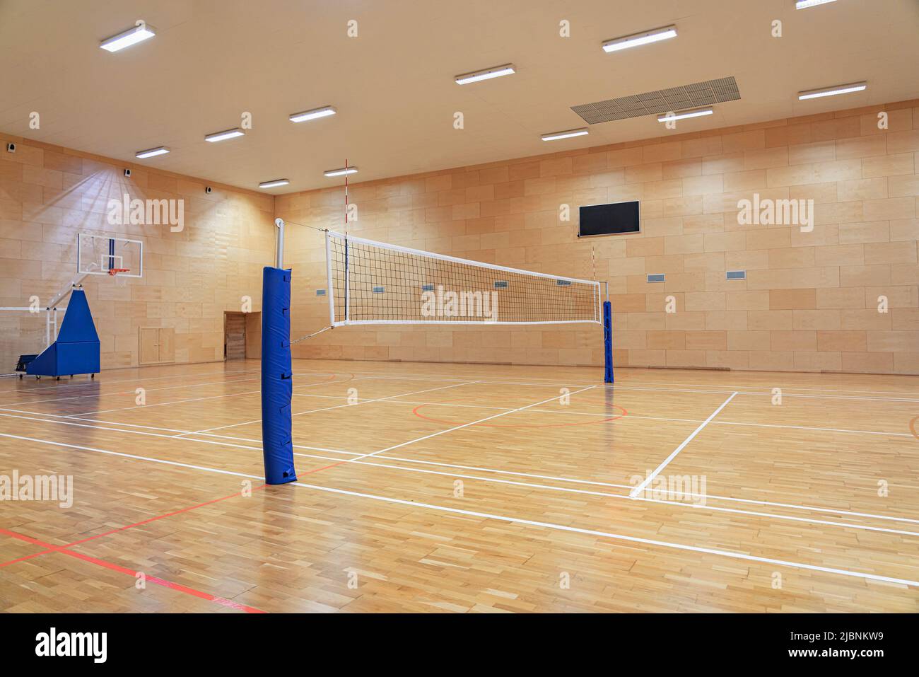 Volleyball net in an empty gym with a mobile basketball hoop in the background Stock Photo