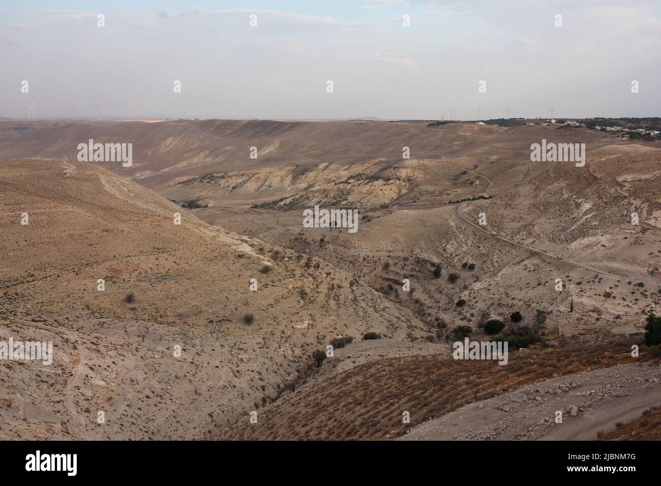 Desert landscape view of sunny rocky cliff with wind turbines in view taken from Shobak Castle, Jordan Stock Photo