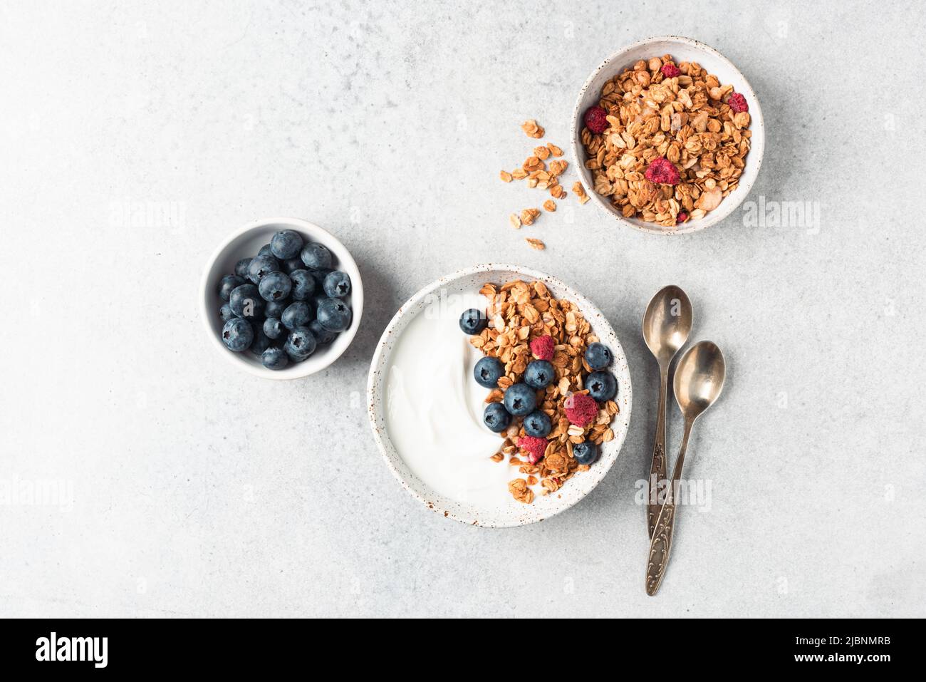 Greek yogurt bowl with granola and berries on grey concrete table background, top view, copy space for text or design elements Stock Photo