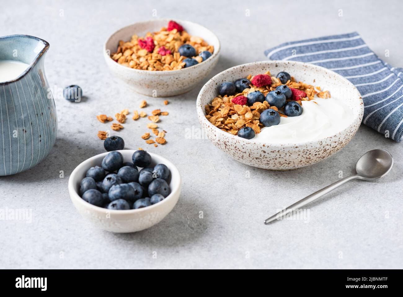 Granola yogurt bowl with blueberries and dried raspberries on grey concrete table background, closeup view Stock Photo