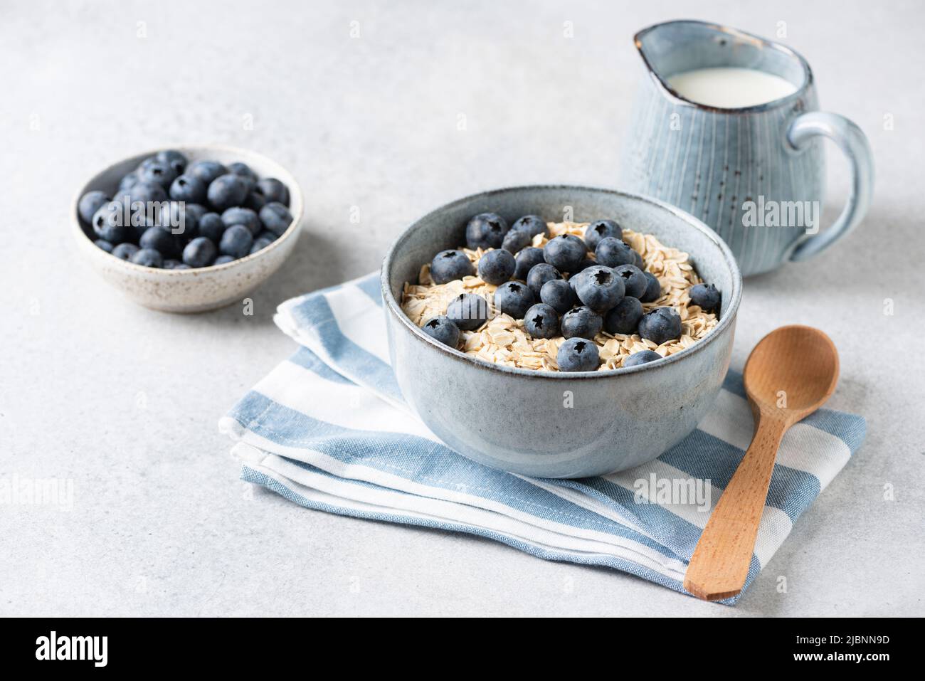 Uncooked oatmeal porridge with blueberries in bowl. Oat flakes, rolled oats. Breakfast meal concept Stock Photo