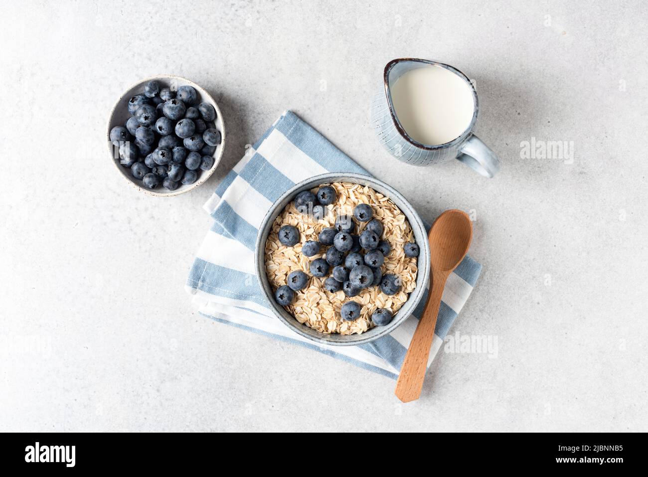 Dry rolled oats, blueberries and milk. Concept of healthy breakfast oatmeal porridge or muesli. Top view Stock Photo