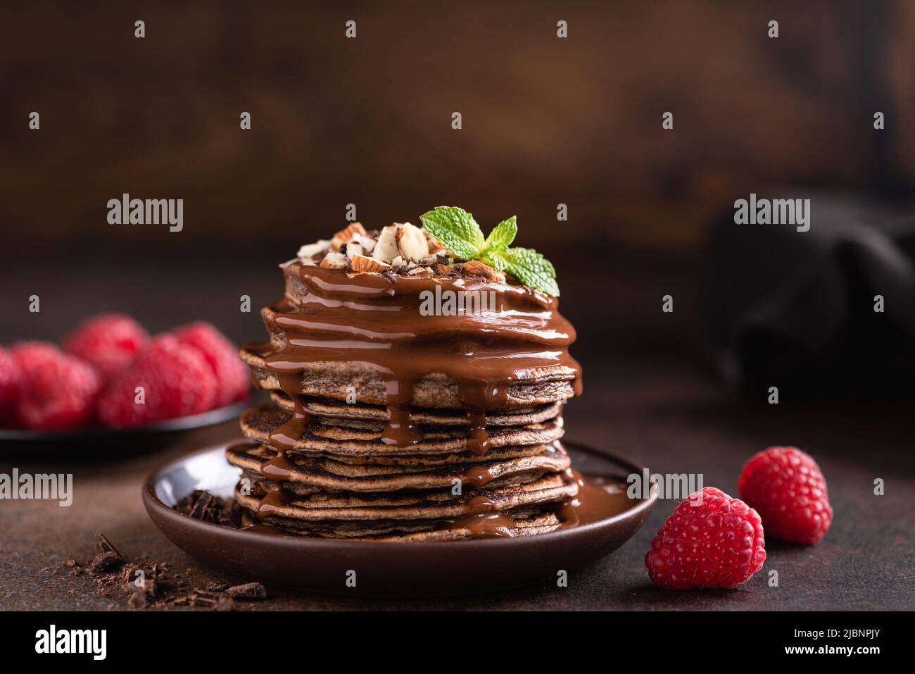 Stack of chocolate pancakes with sauce and raspberries Stock Photo