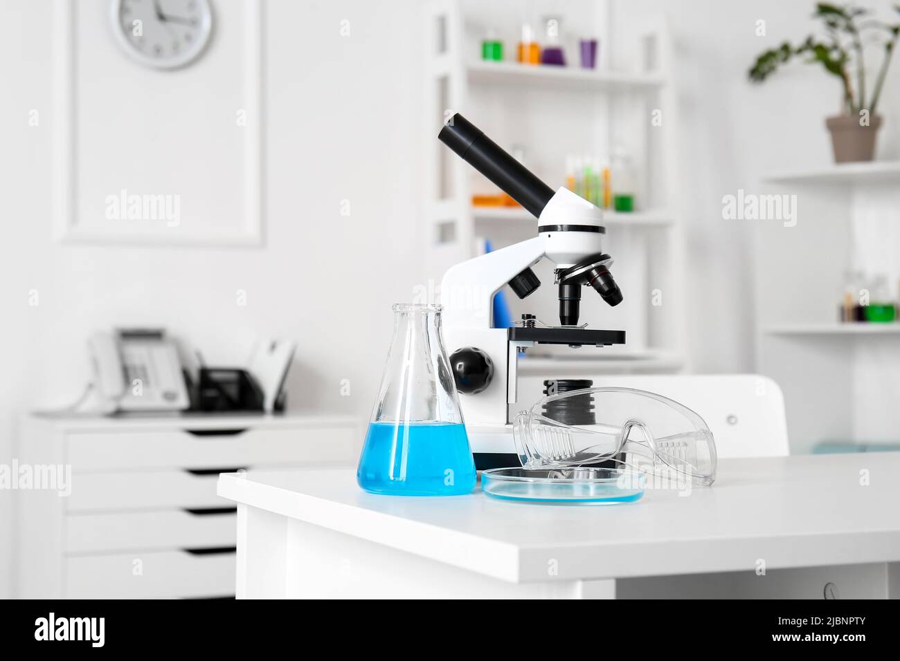 Modern microscope and chemical glassware on table in medical laboratory ...