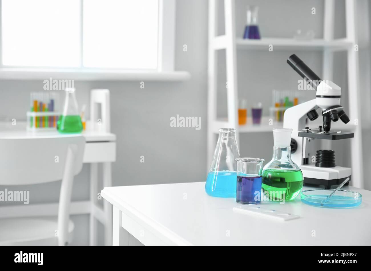 Modern microscope and chemical glassware on table in medical laboratory ...