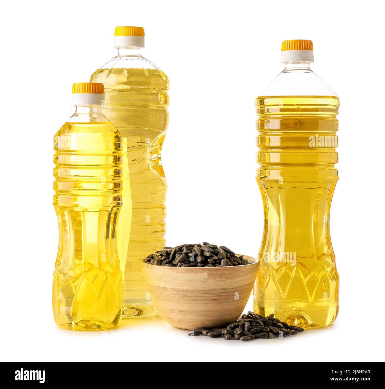 Different bottles of oil and bowl with sunflower seeds on white ...