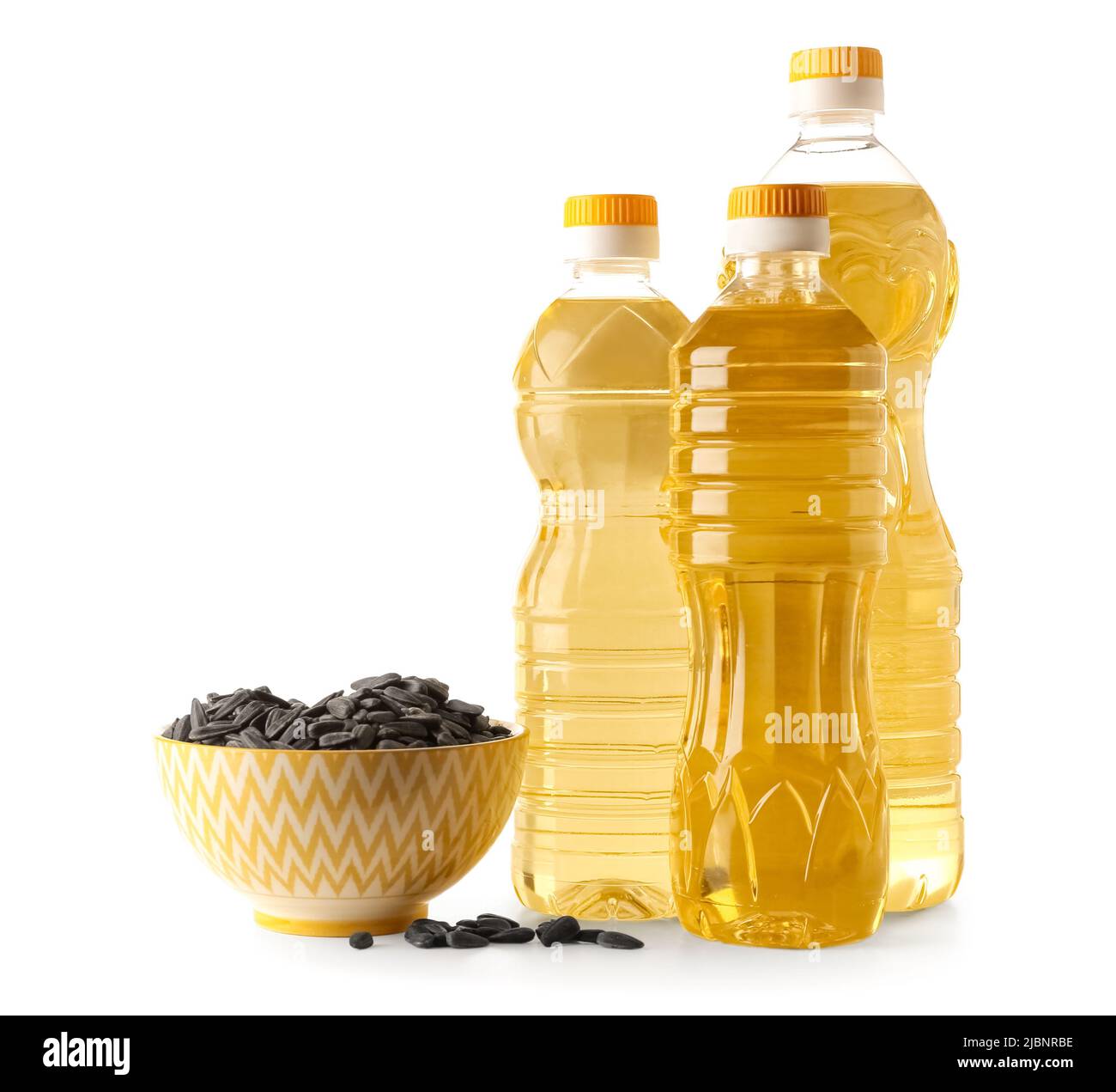 Bottles of fresh oil and bowl with sunflower seeds on white background ...