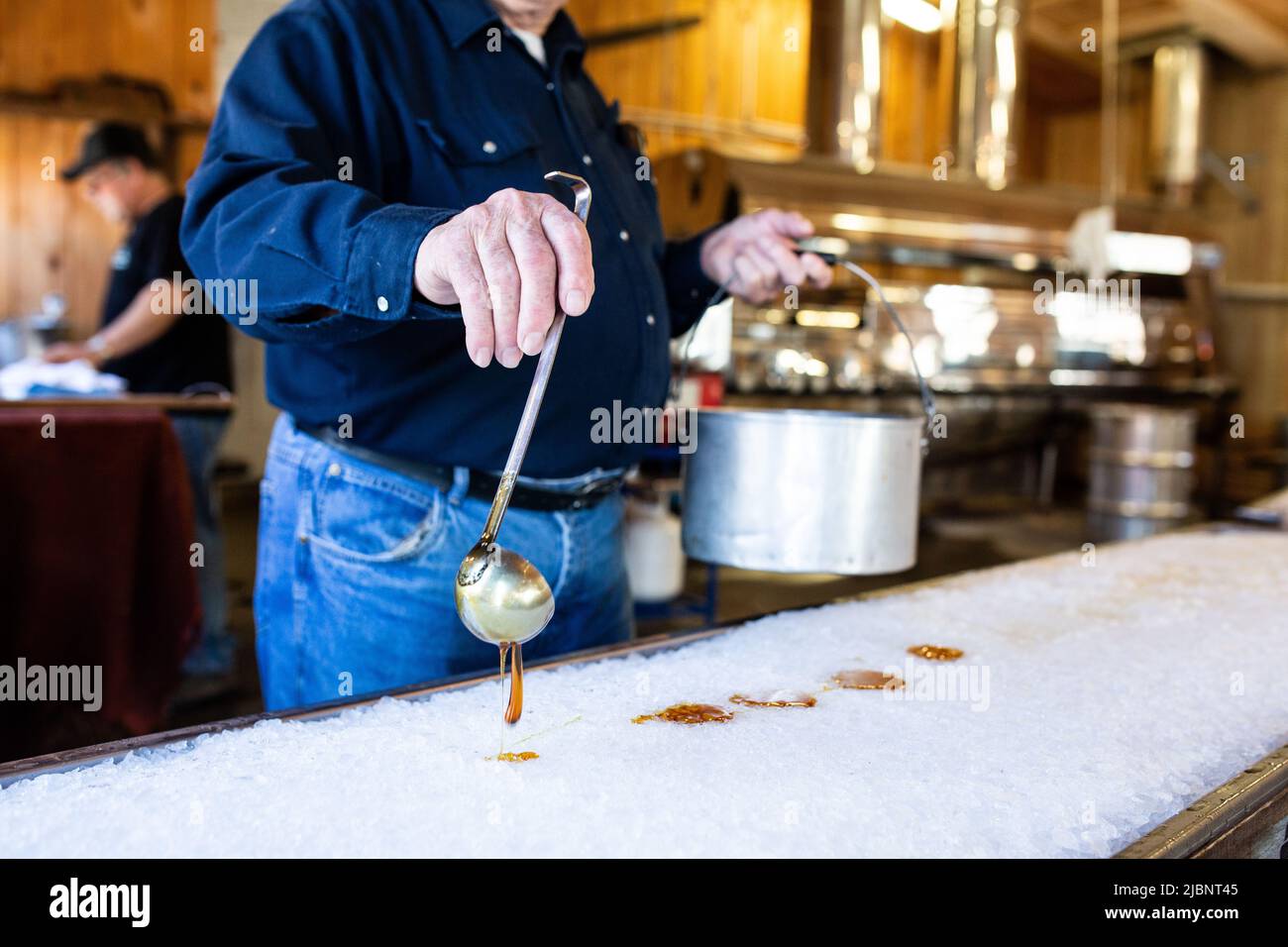 Boiling maple syrup being poured onto snow to make maple syrup sweets