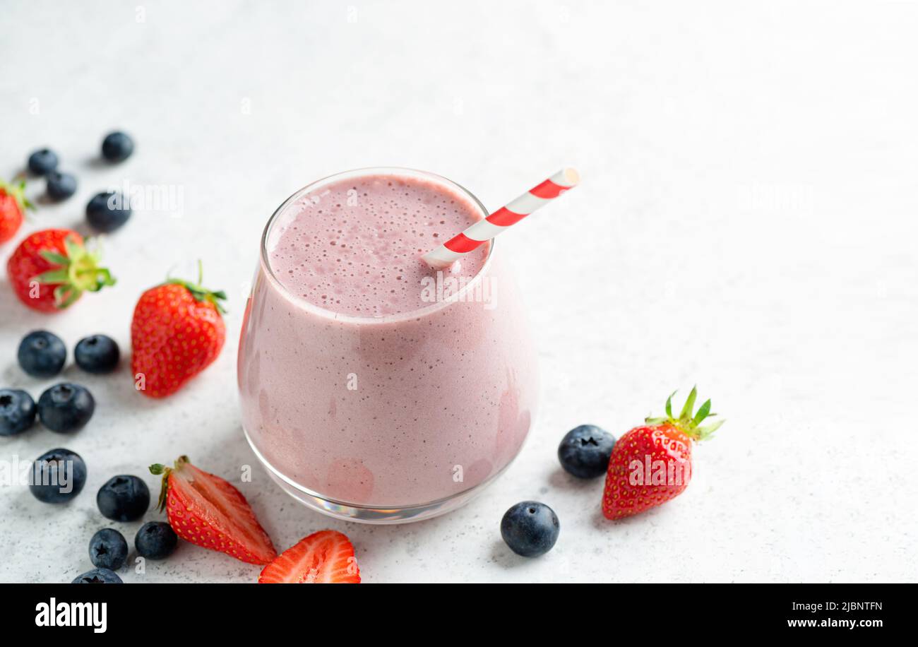Strawberry blueberry smoothie or milkshake on grey concrete background with copy space Stock Photo