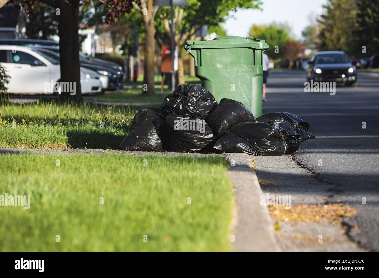 Green plastic trash can full trash bags Stock Photo Alamy