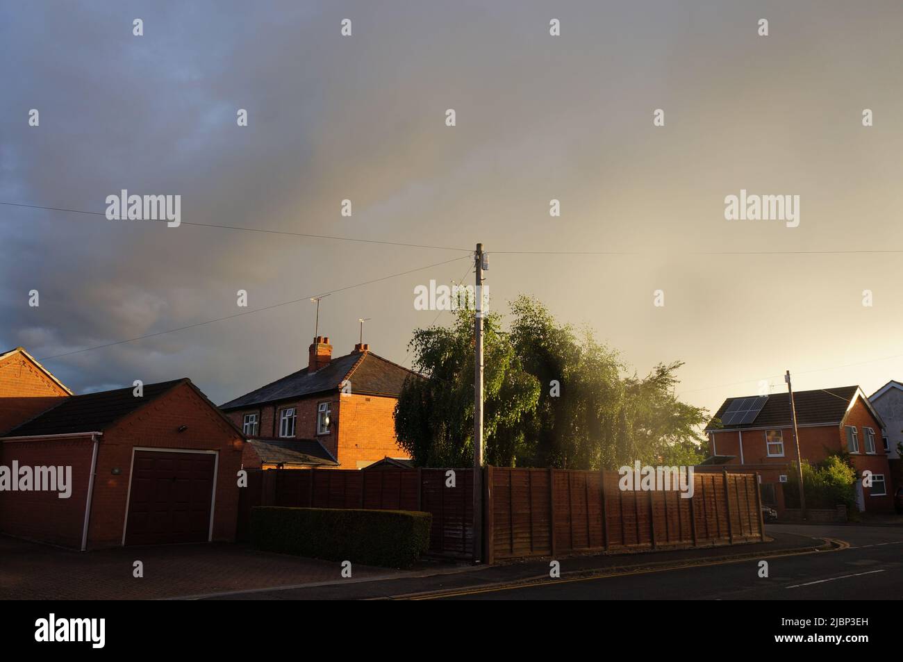 Unusual grey sky & sunlight falling on a suburban street Stock Photo