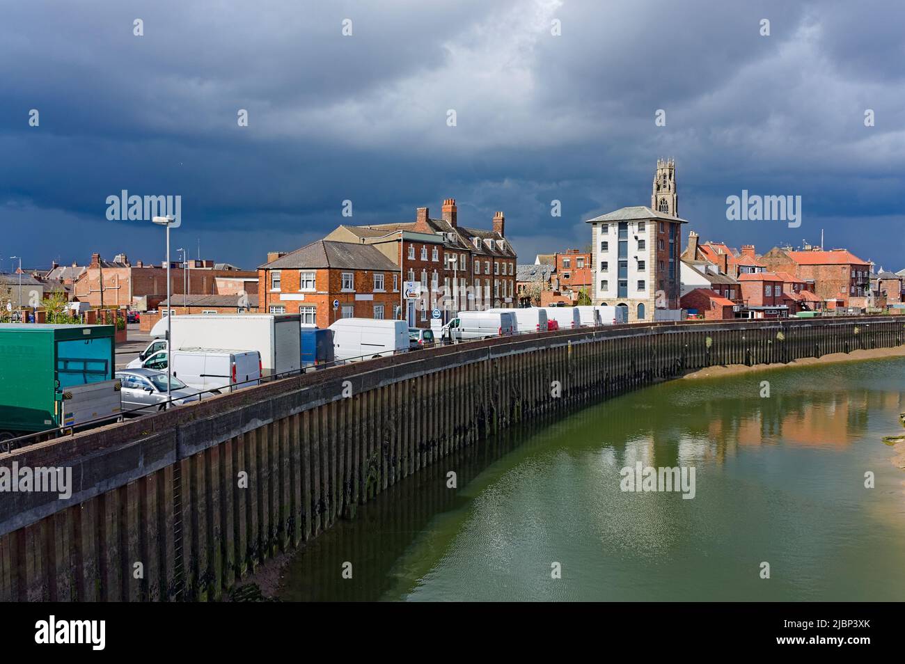 Sunlit buildings near High Street by the river Haven (Witham) with dark clouds in the sky Stock Photo