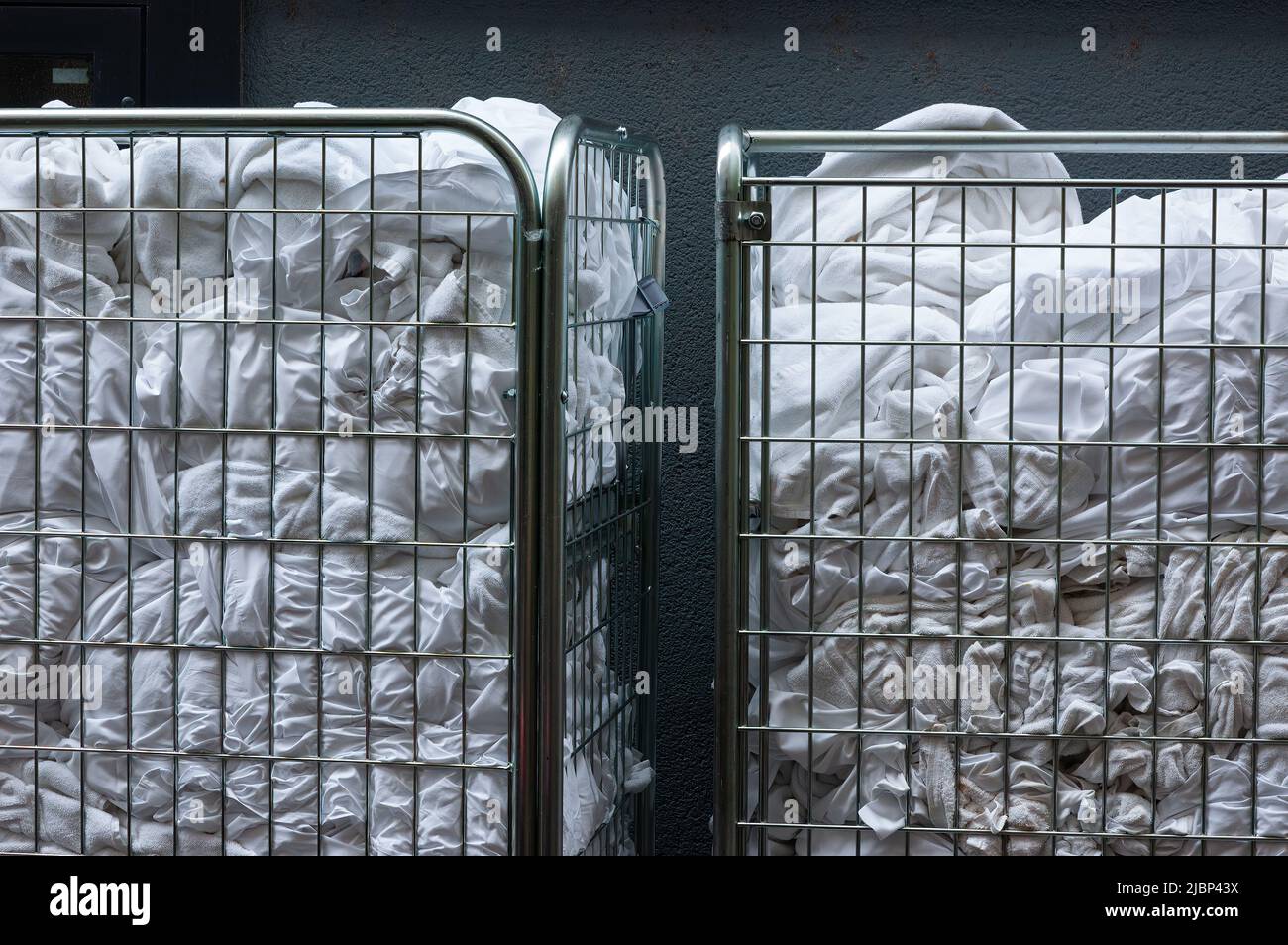 Strollers with dirty white bed linen and towels in front of the hotel