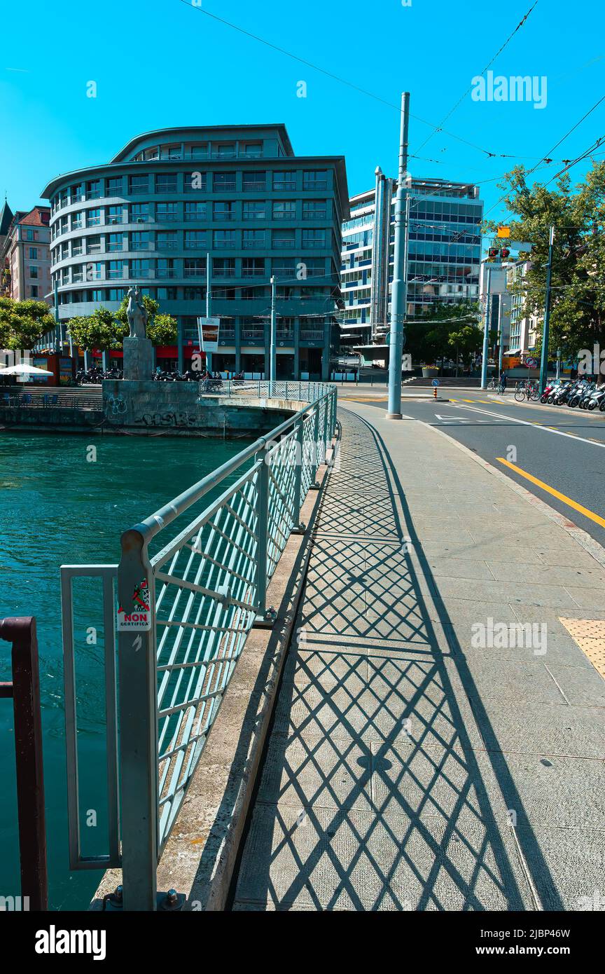 Geneva, Switzerland - June 3, 2022: The buildings in Geneva and the bridge over the Rhone River, reflecting the shadow of the fence Stock Photo