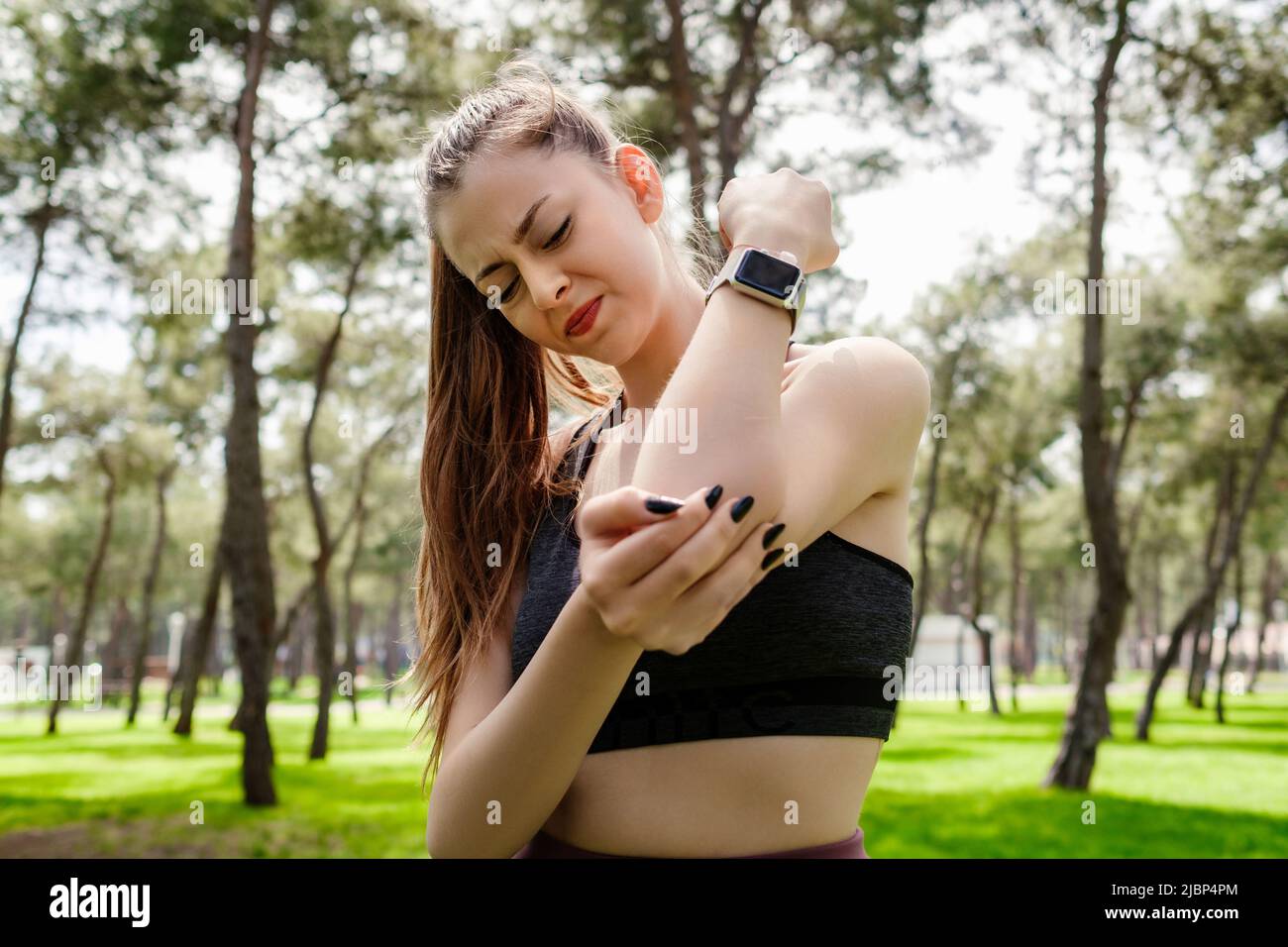 Beautiful woman wearing sports bra standing on city park