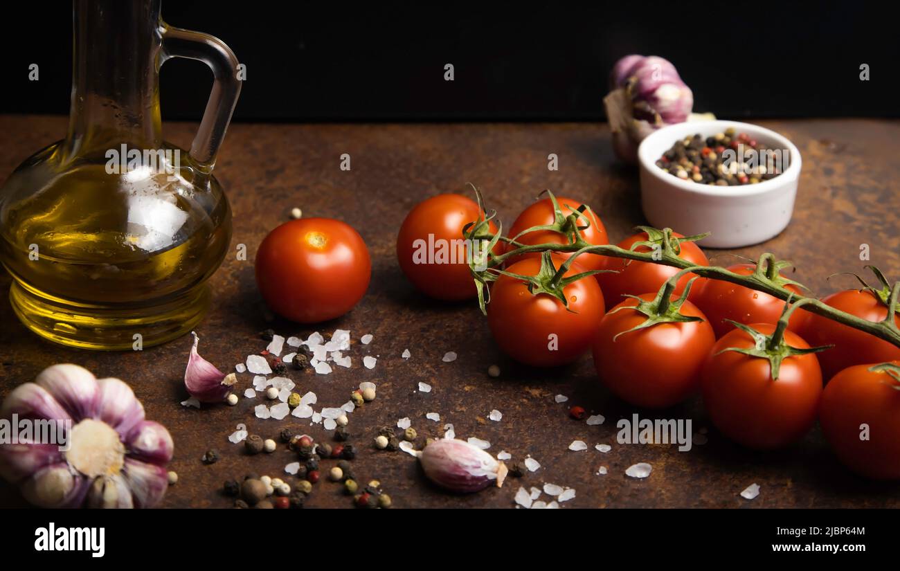 General view of cherry tomatoes, garlic, pepper mixture, edible sea salt, a container with olive oil. Stock Photo
