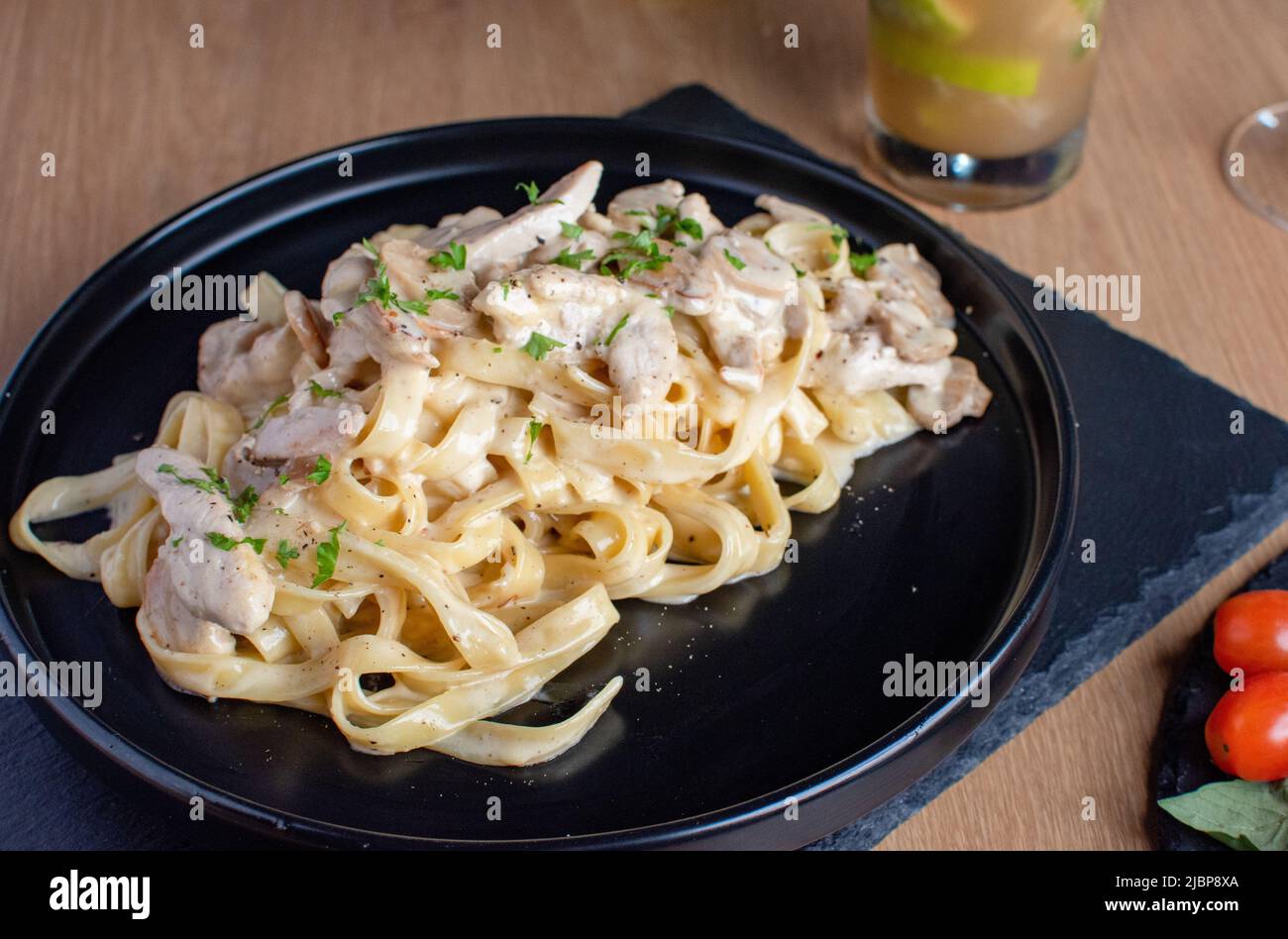 Alfredo chicken pasta with white sauce in a black plate Stock Photo - Alamy
