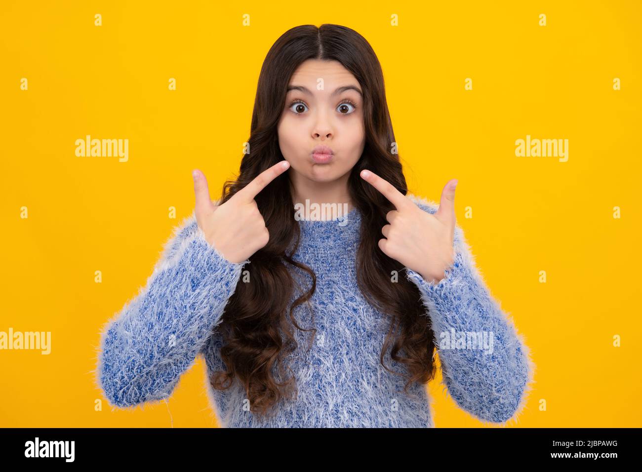 Funny face. Beautiful teen child pinching cheeks with index finger, showing cheek, funny photo, amusing, aesthetics concept, cheek. Stock Photo