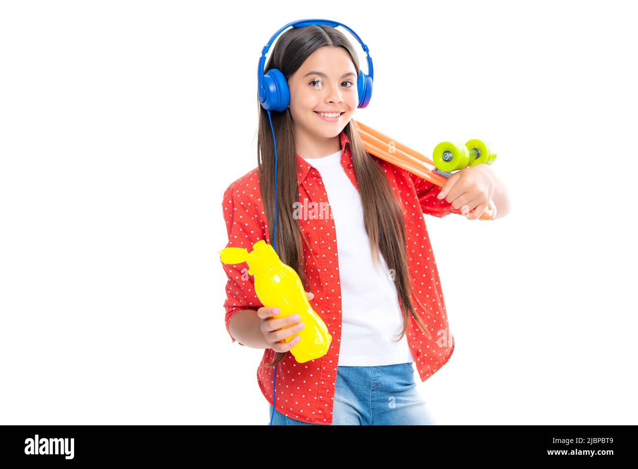 Teenagers lifestyle, casual youth culture. Teen girl with skateboard and headphones over white isolated studio background. Cool modern teenager in Stock Photo