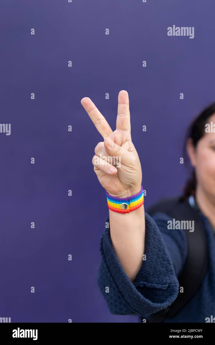 Detail of arm and hand of woman wearing gay wristband on purple background Stock Photo