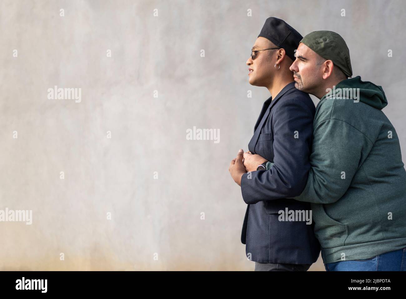 Gay latin couple wearing fashionable hats hugging in the street. Copy space Stock Photo