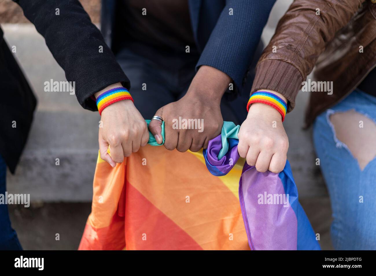 Multi ethnic lgbt gruup wearing lgbt wristbands, holding lgbt flag. Stock Photo