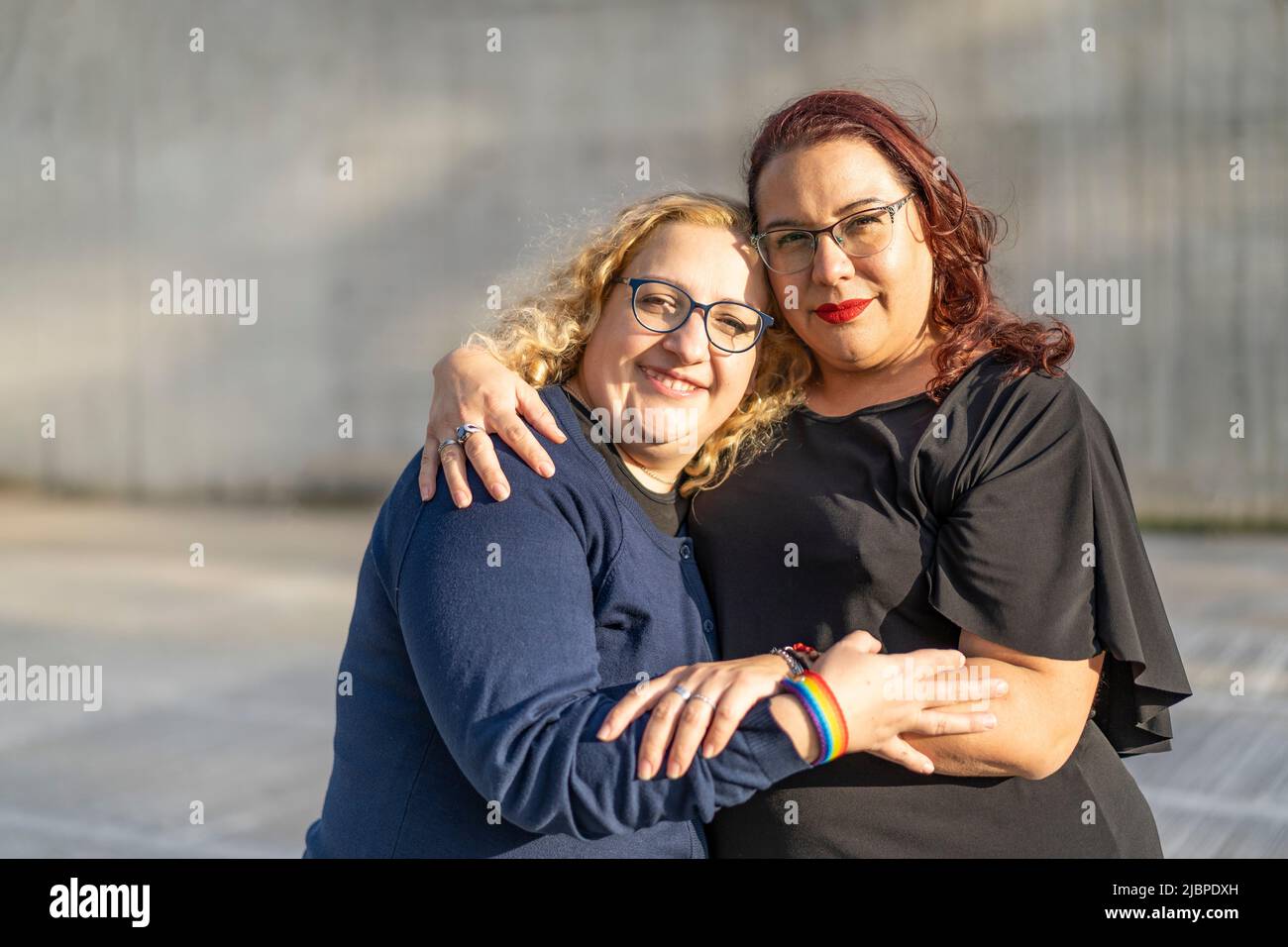 Couple of lesbian women hugging in a park looking at the camera Stock Photo