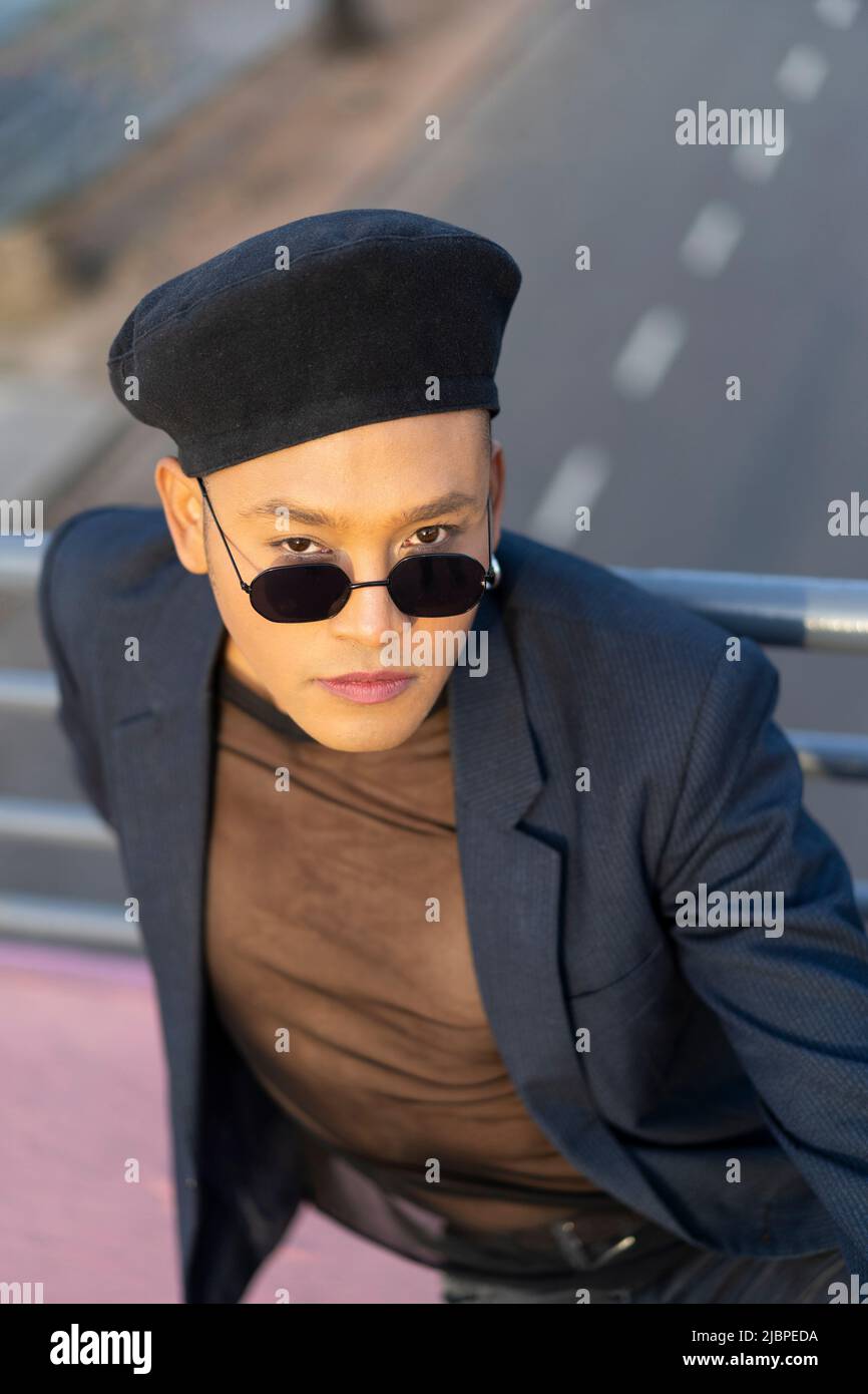 Latino gay male with makeup wearing trendy hat posing on a bridge Stock Photo