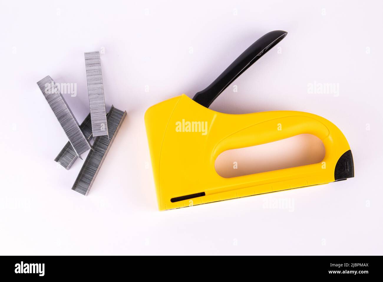 Yellow staple gun and metal staples on a white background Stock Photo