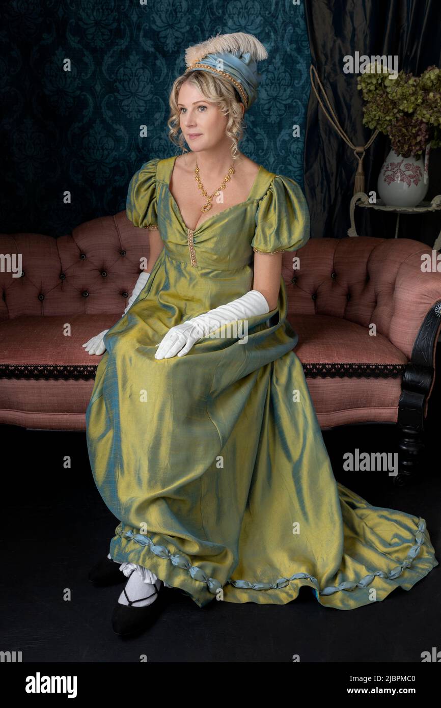 A Regency woman wearing a green shot silk dress and sitting in her drawing room Stock Photo