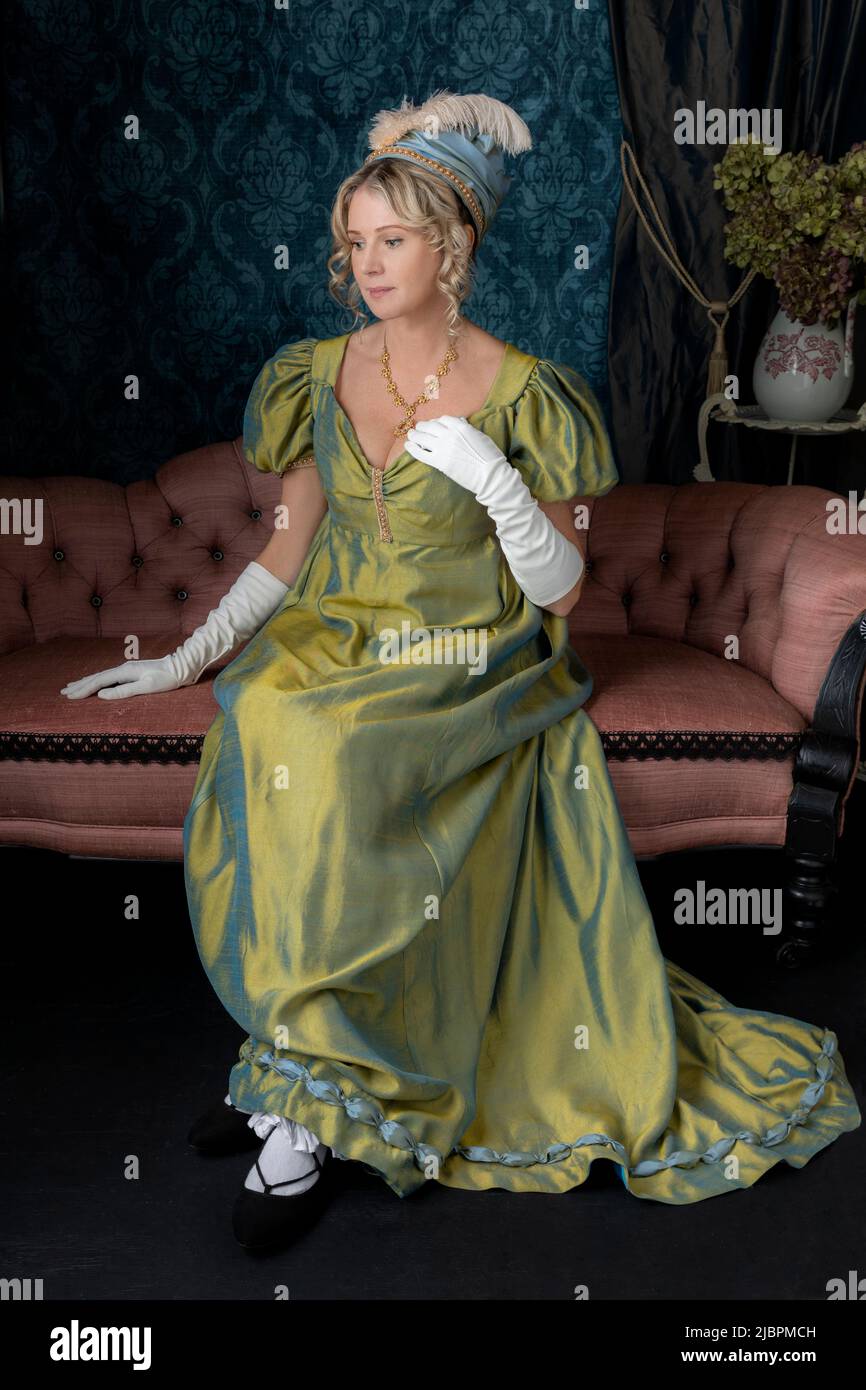 A Regency woman wearing a green shot silk dress and sitting in her drawing room Stock Photo